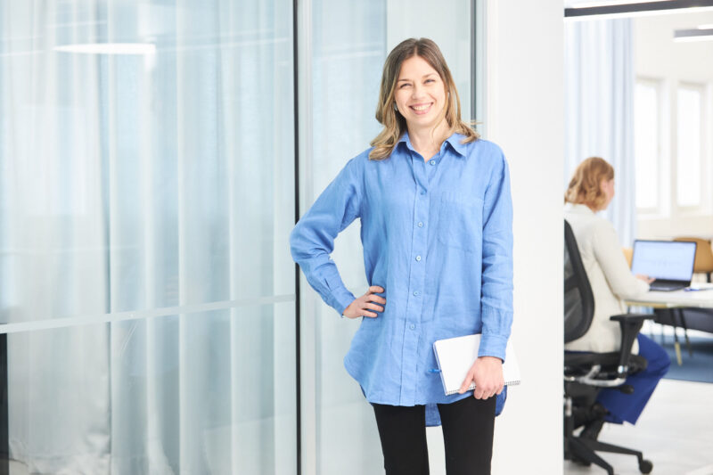 Rekrytoija seisoo iloisesti ja hymyilee kameralle.