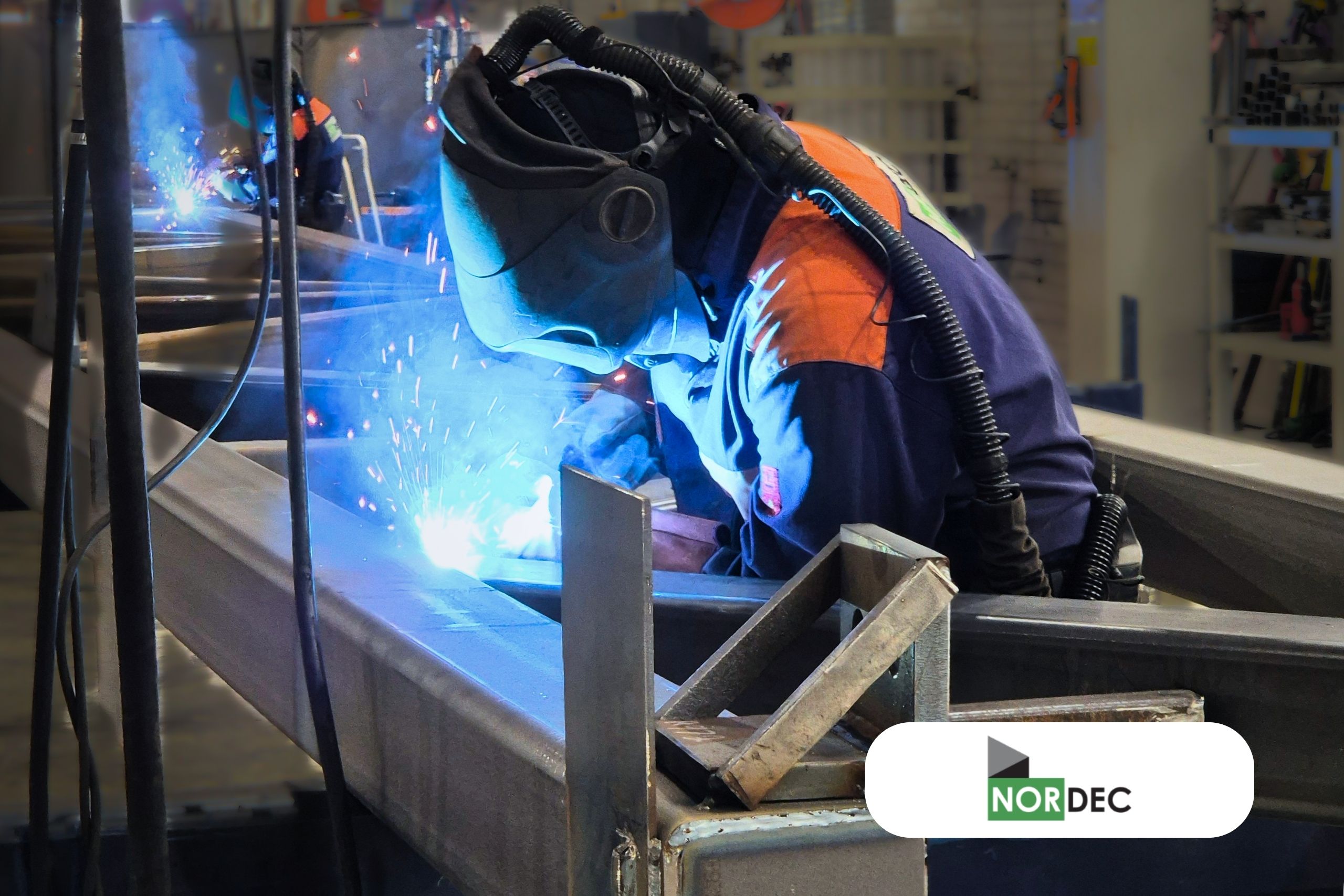 Kuvassa on suojavarusteisiin ja hengityssuojaimeen pukeutunut hitsaaja hitsaamassa teräspalkkia